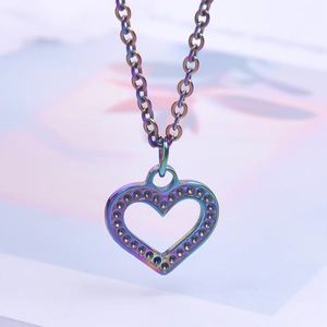 Macro shot of heart-shaped rainbow stainless steel pendant with textured edges on a necklace