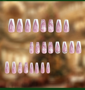 Detail of pink press-on nails with white snowflakes and French V-tip design