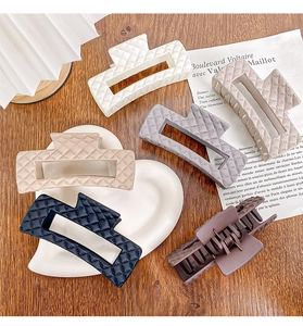 Quilted texture hair claws in white beige gray and black shown on a wooden table