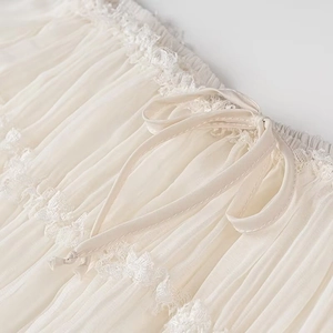 Dettaglio ravvicinato di tessuto a pieghe crema con pizzo e un elegante fiocco