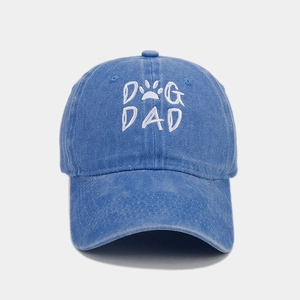 Close-up of white DOG DAD embroidery and paw print on washed blue cotton baseball cap