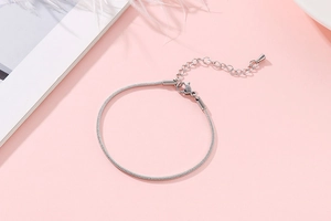 Detailed close-up of a silver snake bone chain bracelet with adjustable lobster clasp