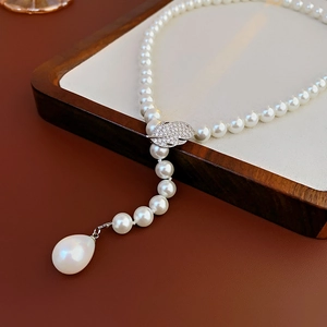 Close-up of pearl necklace with zircon leaf clasp and large teardrop pearl pendant