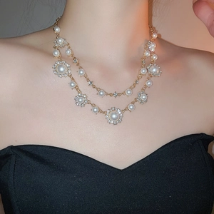 Detailed close-up of double-layer necklace with rhinestones and white pearls on model