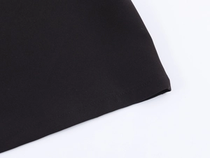 Close-up detail of the black polo shirt hem showing high-quality precision stitching
