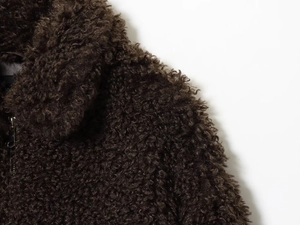 Detailed macro view of the premium brown faux shearling fleece texture on the jacket collar