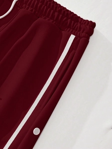 Close-up of deep red jogger pants featuring side stripes and white button details