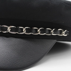 Detail of silver metal chain with black leather weaving on wool navy cap brim