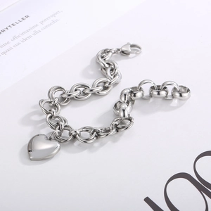 Detailed shot of a silver thick chain link bracelet featuring a heart-shaped pendant
