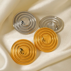 Minimalist spiral twist gold and silver heart earrings set on elegant beige silk fabric