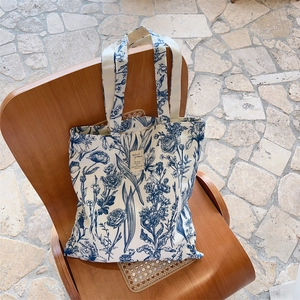Detail of canvas tote bag with blue botanical print on vintage wooden chair