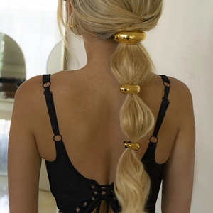 Detailed back view of gold metal hair rings set on a bubble braid hairstyle