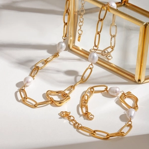 Close-up of golden paperclip chain set with baroque pearls and irregular heart charms