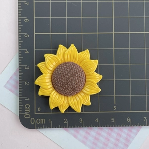 Detailed view of a 4.5cm yellow resin sunflower DIY accessory on a measuring scale mat
