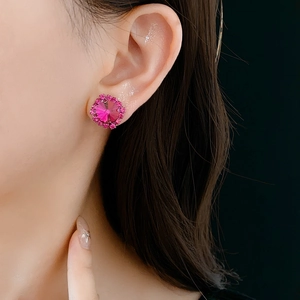 Close-up of elegant pink crystal stud earrings with halo rhinestones on a model ear