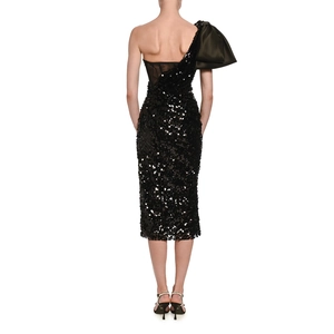 Close-up of a sequined black dress featuring a large satin bow on the one-shoulder design
