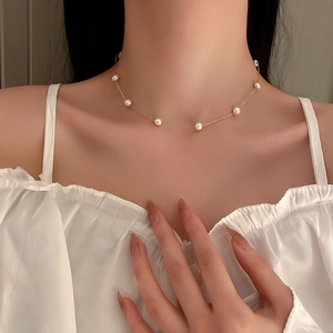 Minimalist gold plated choker necklace with delicate white pearls worn by a model