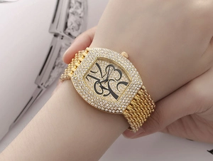 Close-up of luxury gold tonneau watch with sparkling rhinestones and artistic numerals