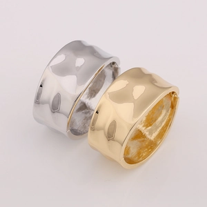 Detail of wide metal bangle with hammered texture and hinge closure in gold and silver
