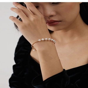 Detail of gold woven pearl bracelet on wrist, elegant retro style for women