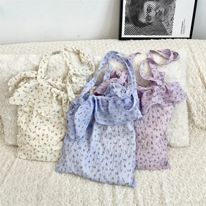 Detailed view of floral tote bags in white, blue, and purple with ruffled edges