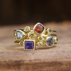 Anillo geométrico de piedras preciosas coloridas sobre una superficie de madera