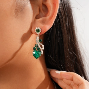 Close-up of elegant flower and heart green gemstone earrings on a female model
