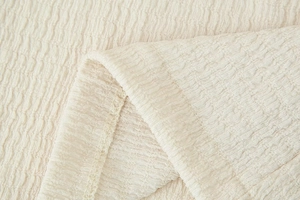 Detail of cream-white seersucker pleated fabric and high-quality stitching on the garment