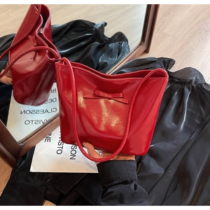 Close-up of red patent leather handbag featuring a stylish bow and sleek shoulder strap