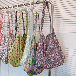 Detailed close-up of various floral cotton tote bags hanging on a rack with pastel patterns