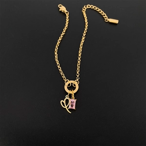 Close-up detail of a gold-plated titanium steel bracelet featuring a pink gemstone pendant