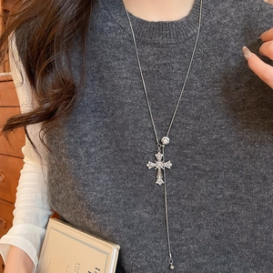 Close-up of a vintage silver cross pendant with rhinestones on a female model with a book