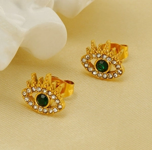 Macro view of gold plated evil eye stud earrings with green center stone and white zircons
