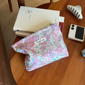 Floral makeup bag with simple wish label on a wooden table for daily storage