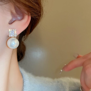 Detail of square zircon stud with a lustrous round pearl drop earring on model
