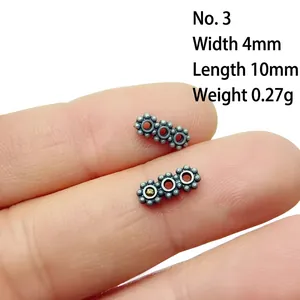 Detailed macro view of retro alloy floral spacers measuring 4mm by 10mm on a fingertip