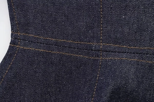 Detailed close-up of dark indigo denim fabric with orange double-needle contrast stitching