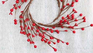 Macro detail of artificial red berries and brown branch texture on a festive wreath