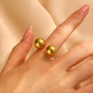 Detail of high-polish double gold spheres on a minimalist stainless steel open ring