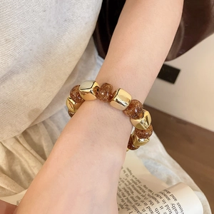 Detailed close-up of acrylic beaded stretch bracelet with gold cubes and amber glitter beads
