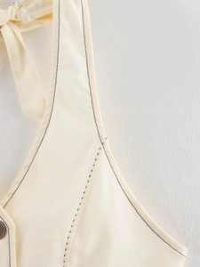 Détail macro du tissu denim beige avec surpiqûres noires sur l'encolure licou