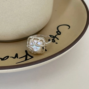 Minimalist silver 925 open ring with baroque pearl on a ceramic coffee saucer