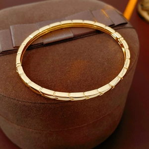 Close-up of gold arrow-textured segmented bracelet on dark velvet jewelry display box