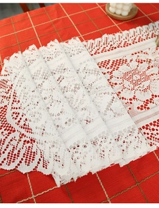 Detail showing white lace table runner with intricate hollow patterns and knit tassels