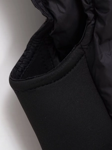 Détail du gilet noir coupe-vent montrant les poignets côtelés et le tissu nylon