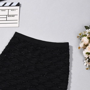 Gros plan sur une jupe noire taille haute avec texture ondulée 3D sur socle gris