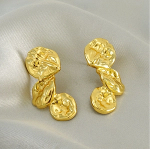 Detail of French vintage irregular lava earrings in gold finish with hammered texture
