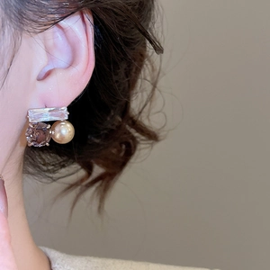 Détail de boucles d'oreilles avec zircon carré et cristal violet portées par un mannequin