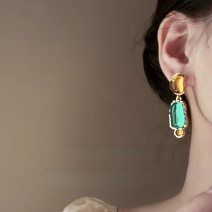 Detail view of vintage irregular resin earrings featuring amber and teal gemstones