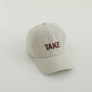 Détail de la texture velours côtelé et broderie TAKE sur la casquette beige enfant